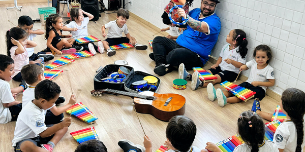 uma turma de alunos do infantil do Colégio Talento participando de uma aula de música, com seus xilofones coloridos