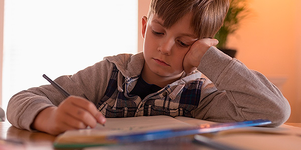 Menino triste estudando porque não tem dificuldade com matemática. 