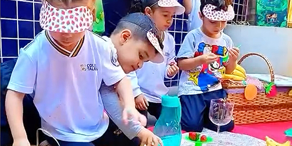 Alunos mexendo nas frutas durante a aula de inglês