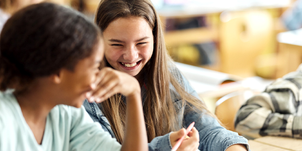 Menina sorri segurando lápis enquanto o Colégio Talento trabalha as competências socioemocionais dos alunos. 