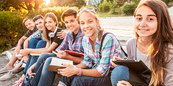 vários adolescentes juntos sentados e sorrindo 